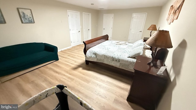 bedroom with light wood-type flooring and multiple closets