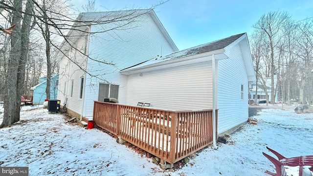 snow covered property featuring central AC unit and a wooden deck