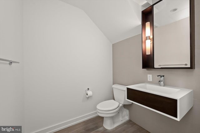 bathroom featuring hardwood / wood-style flooring, vanity, toilet, and lofted ceiling