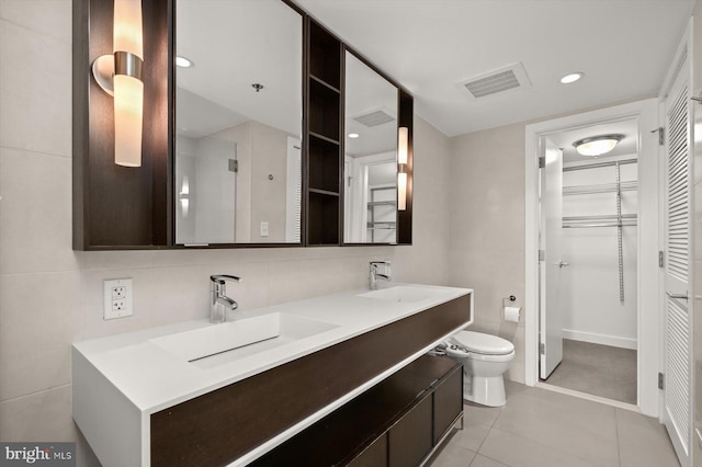 bathroom featuring tile patterned floors, vanity, tile walls, and toilet