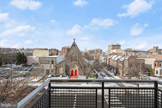 snow covered back of property with a view of city