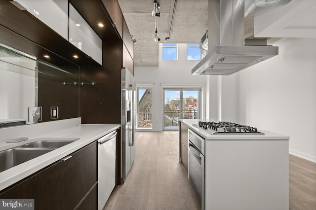 kitchen with track lighting, white cabinets, light wood-type flooring, appliances with stainless steel finishes, and island exhaust hood