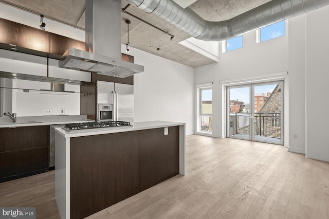 kitchen with sink, stainless steel appliances, light hardwood / wood-style floors, island range hood, and a kitchen island