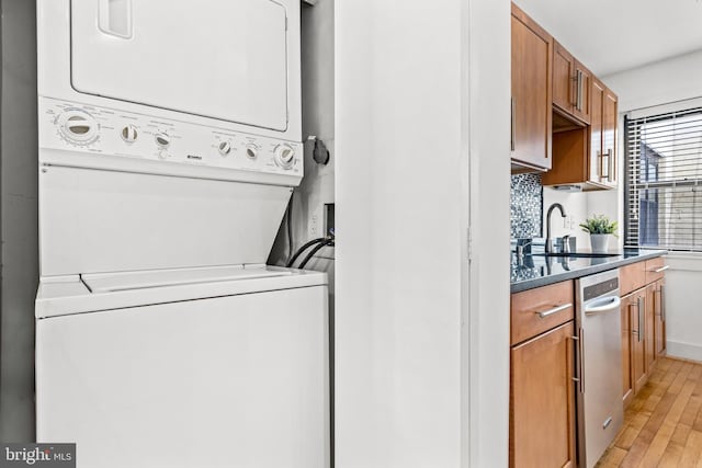 washroom with light hardwood / wood-style floors, stacked washer / dryer, and sink