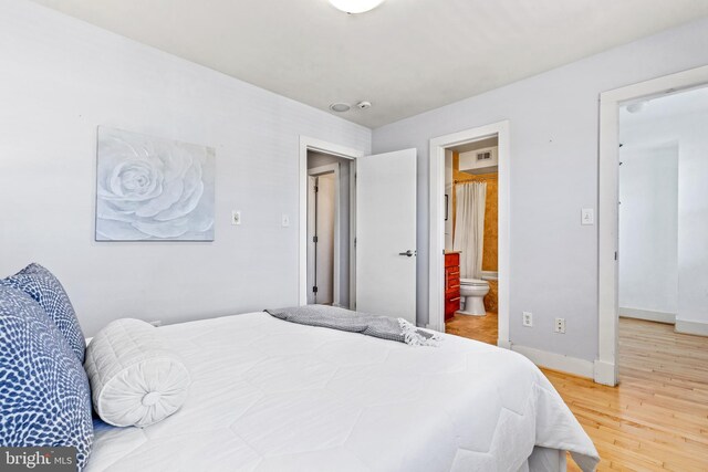 bedroom featuring hardwood / wood-style flooring and ensuite bath