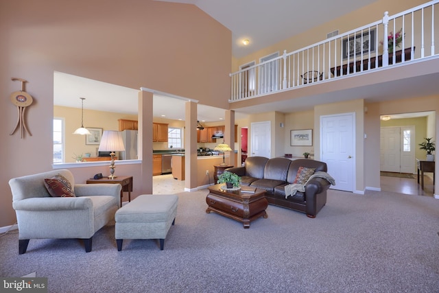 carpeted living room with high vaulted ceiling and plenty of natural light