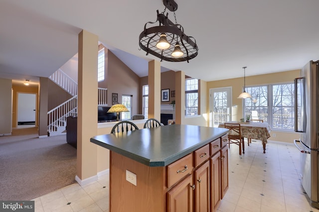 kitchen featuring hanging light fixtures, light colored carpet, a center island, high end refrigerator, and lofted ceiling