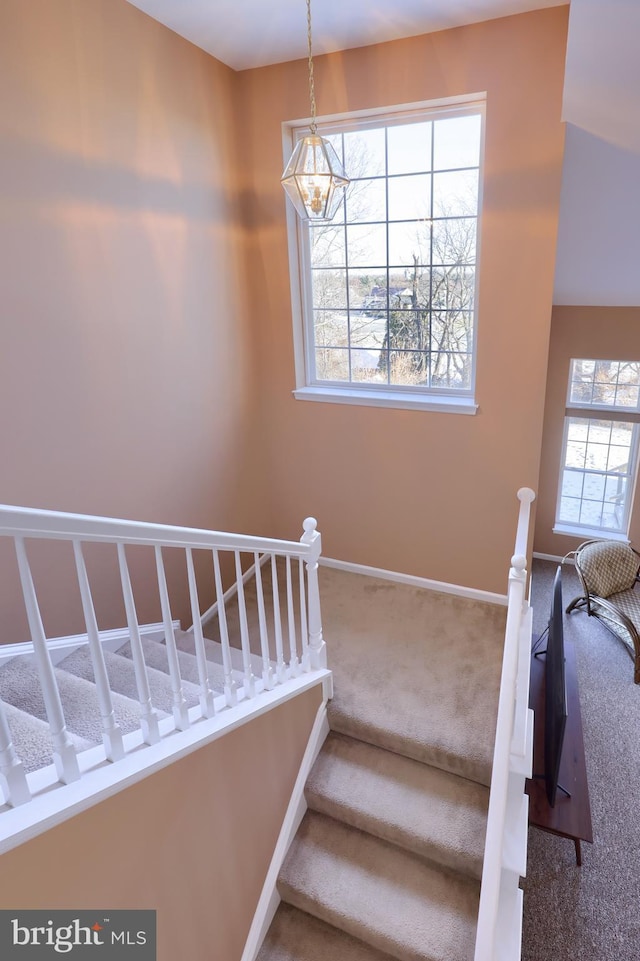 staircase with carpet flooring and an inviting chandelier