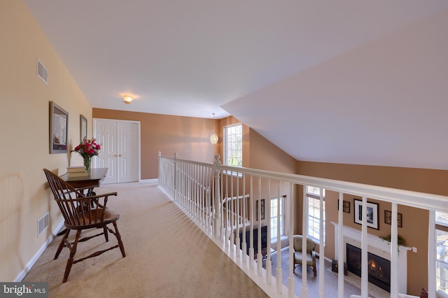 hallway featuring lofted ceiling and light carpet