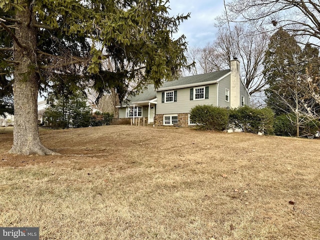 view of front facade featuring a chimney and a front lawn