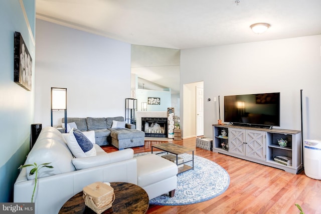 living room with hardwood / wood-style floors, vaulted ceiling, and a tiled fireplace