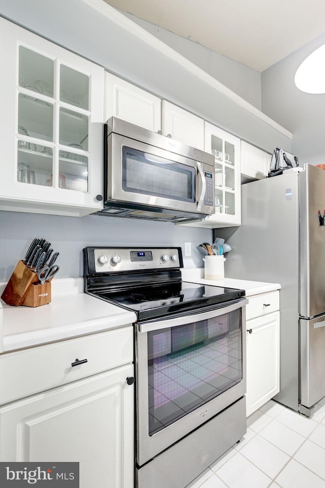 kitchen featuring light tile patterned floors, stainless steel appliances, and white cabinetry