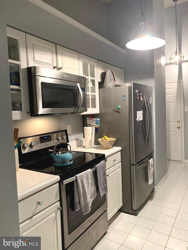 kitchen with white cabinets, decorative light fixtures, light tile patterned flooring, and stainless steel appliances