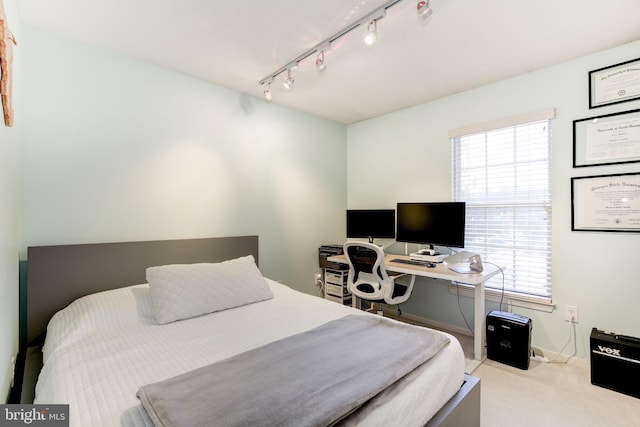 bedroom featuring rail lighting and light colored carpet