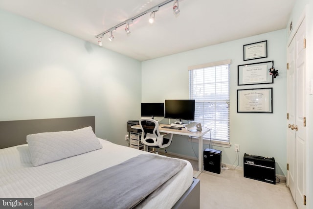 bedroom with light colored carpet, multiple windows, and track lighting