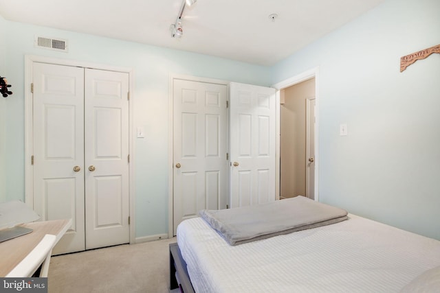 carpeted bedroom with two closets and track lighting