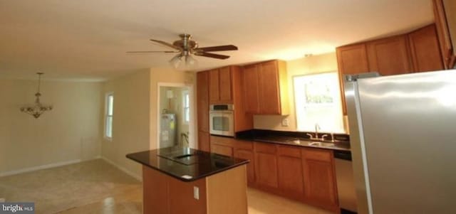 kitchen with a center island, sink, hanging light fixtures, ceiling fan, and stainless steel appliances