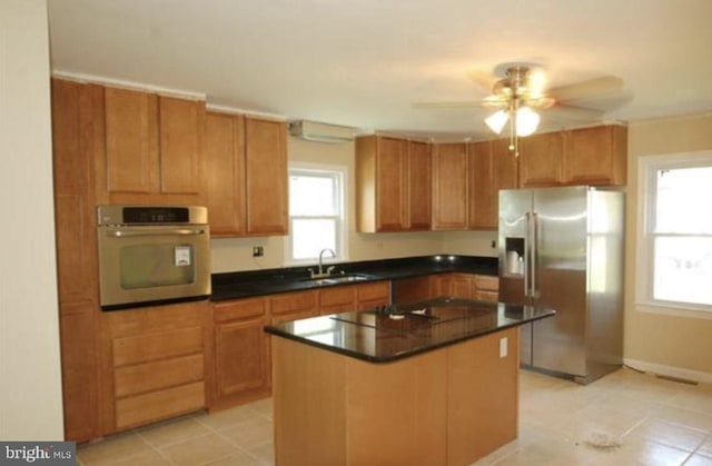 kitchen featuring stainless steel appliances, ceiling fan, sink, a center island, and plenty of natural light