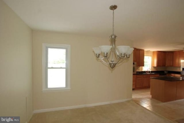 kitchen with light carpet, pendant lighting, ceiling fan with notable chandelier, and a wealth of natural light