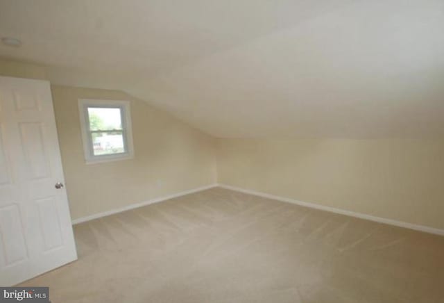 additional living space with light colored carpet and vaulted ceiling