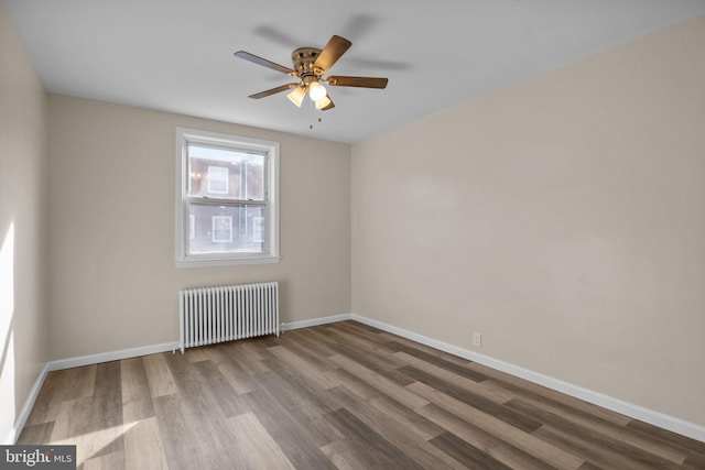 unfurnished room with ceiling fan, radiator heating unit, and hardwood / wood-style flooring