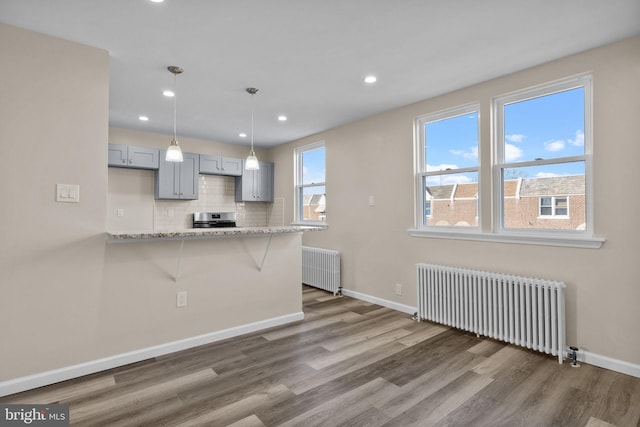 kitchen with stainless steel range, radiator heating unit, pendant lighting, and gray cabinets