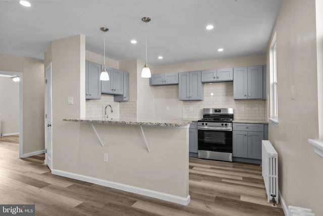 kitchen featuring gray cabinetry, backsplash, gas stove, and radiator