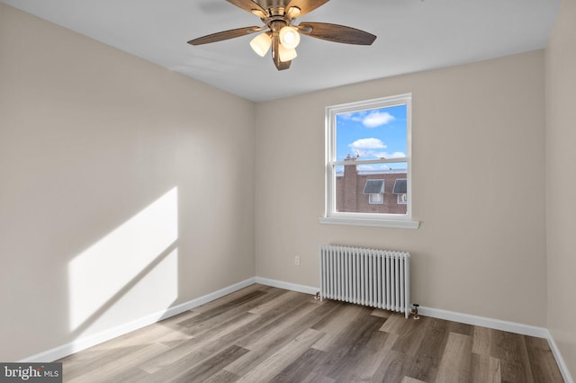 empty room with ceiling fan, radiator heating unit, and hardwood / wood-style flooring