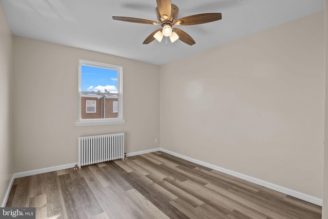 spare room featuring ceiling fan, light hardwood / wood-style floors, and radiator heating unit