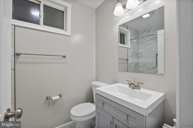 bathroom featuring toilet, a tile shower, and vanity