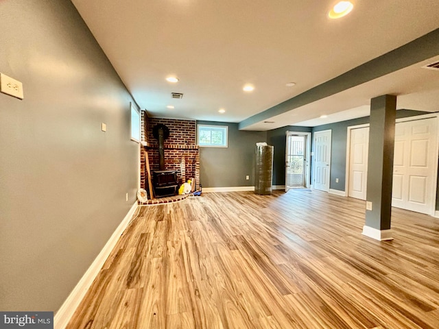 unfurnished living room featuring a wood stove and light hardwood / wood-style flooring