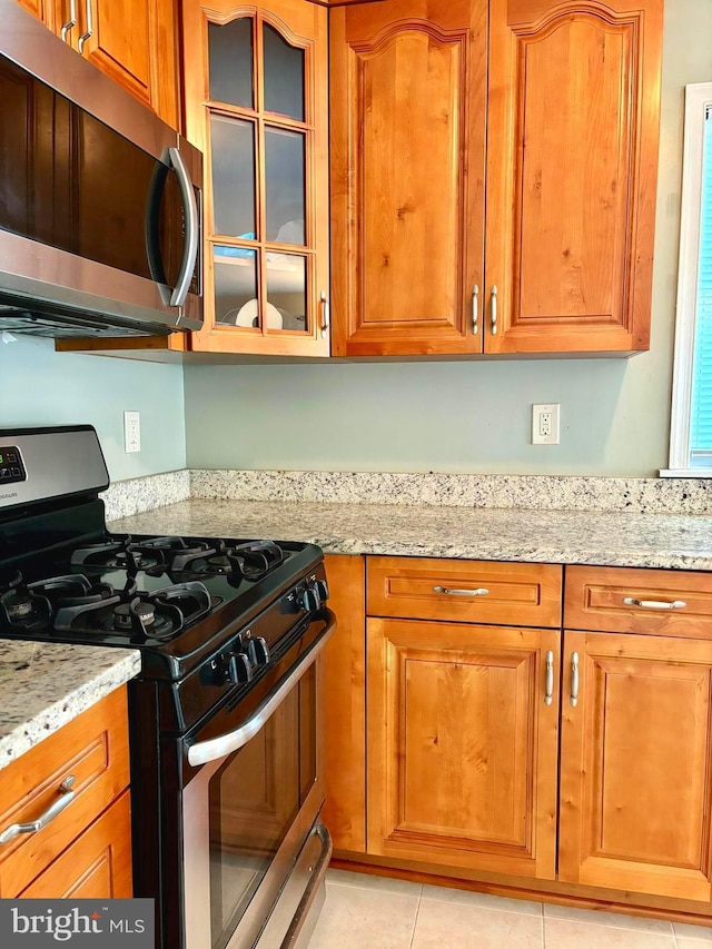 kitchen featuring light stone countertops, light tile patterned floors, and stainless steel appliances