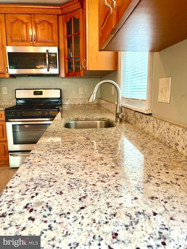 kitchen with light stone countertops, sink, and stainless steel appliances