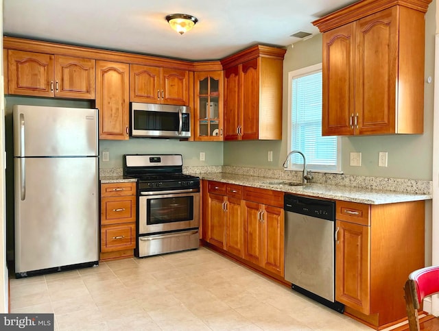 kitchen with light stone countertops, appliances with stainless steel finishes, and sink