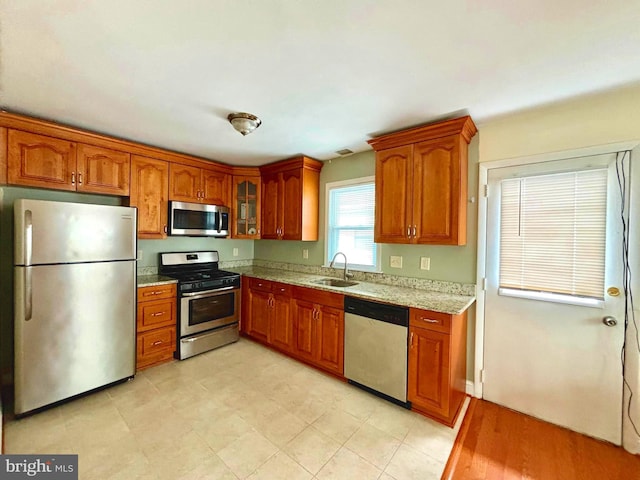 kitchen with light stone countertops, sink, and appliances with stainless steel finishes