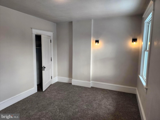 spare room featuring dark carpet