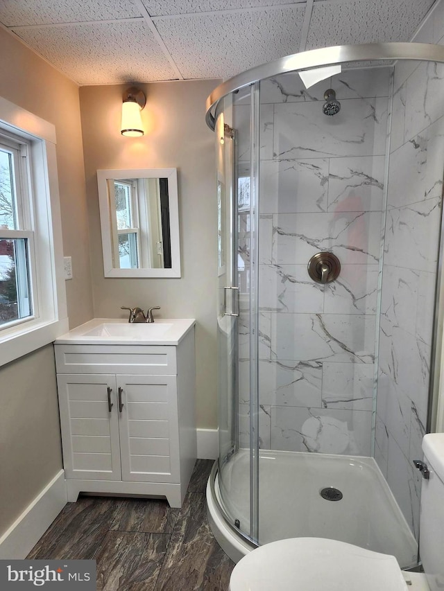 bathroom featuring a paneled ceiling, vanity, toilet, and an enclosed shower