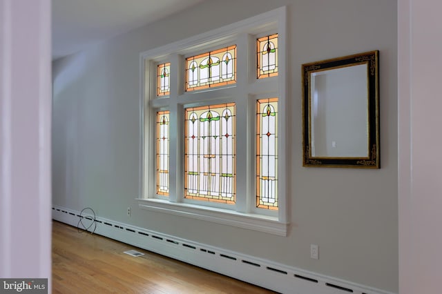 interior space featuring light hardwood / wood-style floors, a healthy amount of sunlight, and a baseboard heating unit