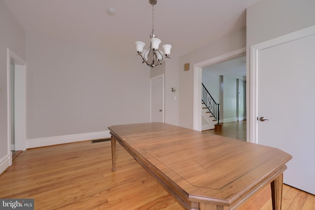 dining area with wood-type flooring and a notable chandelier