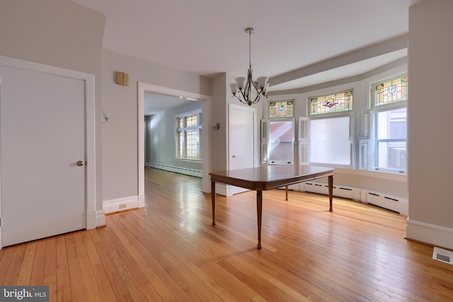 unfurnished dining area with light wood-type flooring, a baseboard heating unit, and a notable chandelier