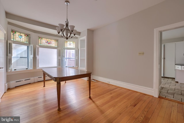 unfurnished dining area featuring a chandelier, light wood-type flooring, and baseboard heating