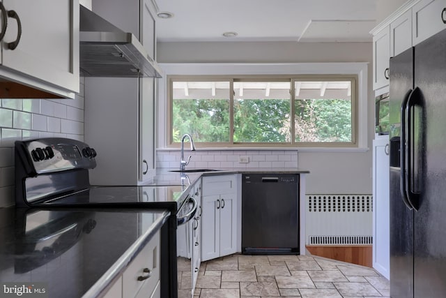 kitchen featuring radiator, wall chimney exhaust hood, sink, black appliances, and white cabinetry