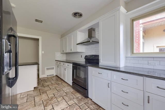 kitchen with white cabinets, stainless steel fridge, black electric range oven, and wall chimney range hood