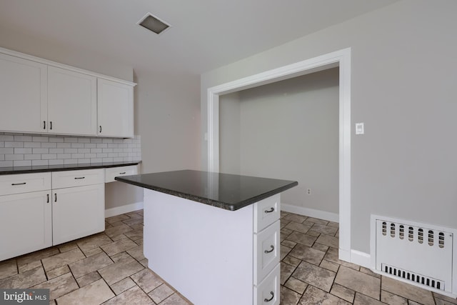 kitchen with a kitchen island, white cabinetry, radiator, and tasteful backsplash