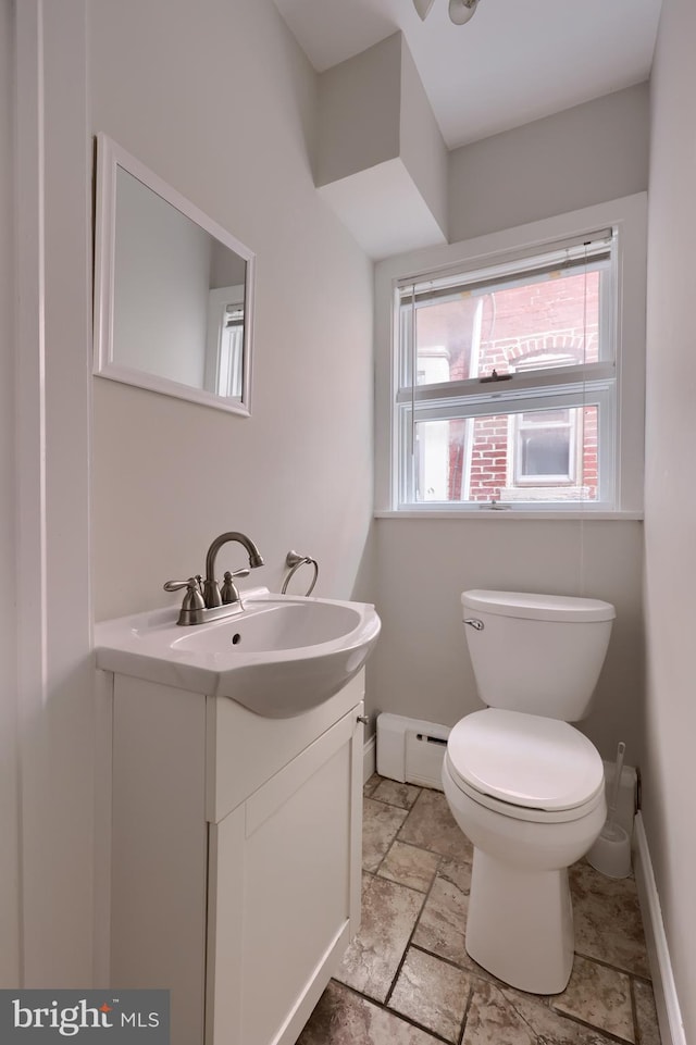 bathroom featuring baseboard heating, a wealth of natural light, vanity, and toilet