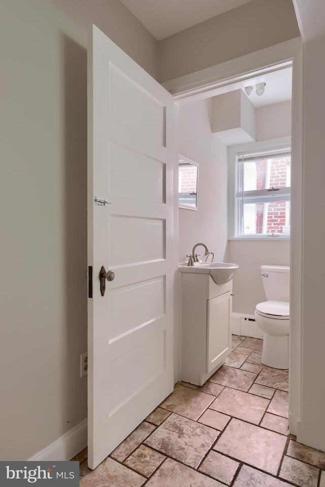 bathroom with vanity, toilet, and a baseboard heating unit