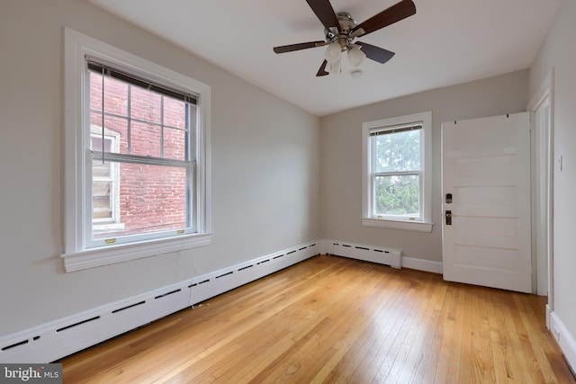 empty room with plenty of natural light, ceiling fan, light hardwood / wood-style floors, and a baseboard heating unit