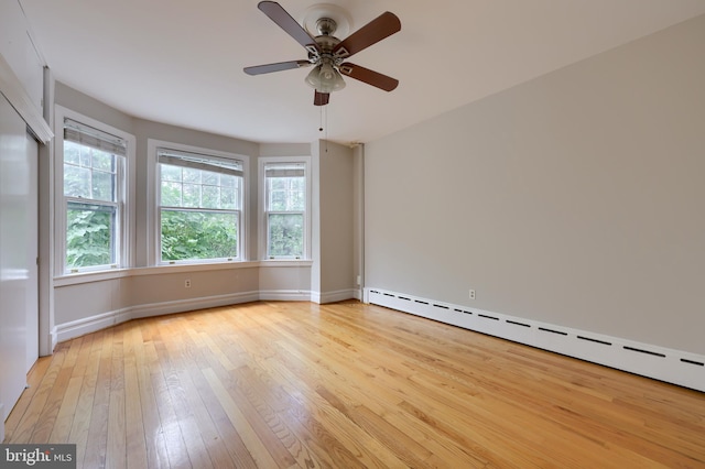 spare room with ceiling fan, a baseboard radiator, and light wood-type flooring