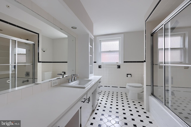 full bathroom with vanity, toilet, tile walls, and enclosed tub / shower combo