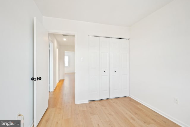 unfurnished bedroom with light wood-type flooring and a closet